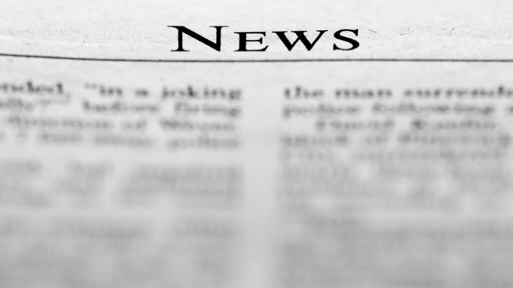 News paper with big placeholder headline and content blurred out.