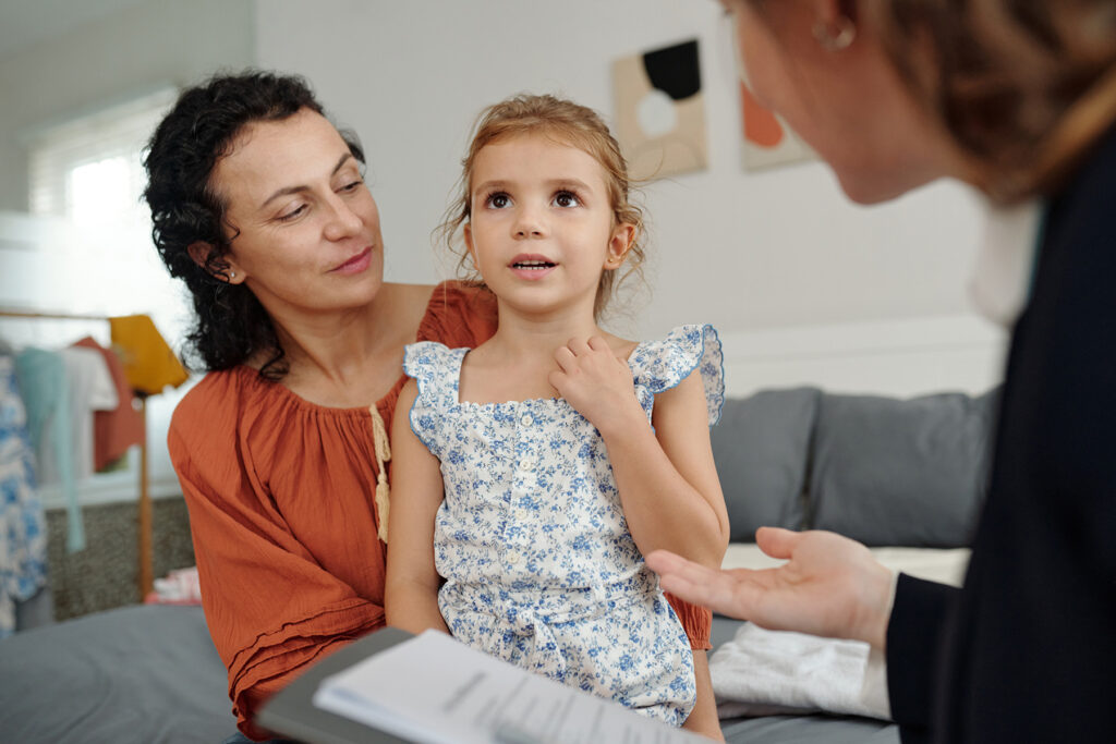 Single mom with her little daughter talking to social worker at home