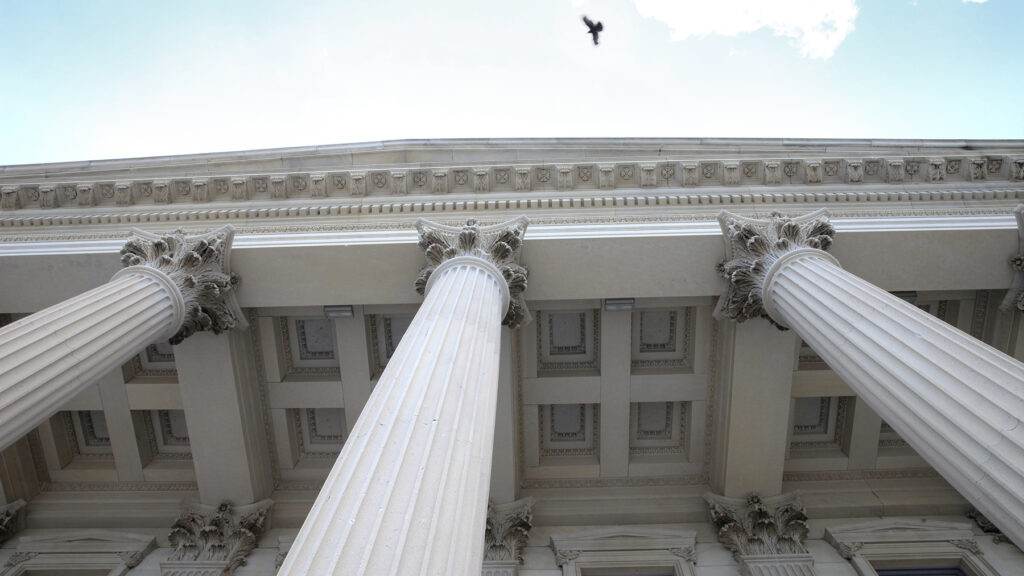 Courthouse exterior with columns and a blue sky overhead.
